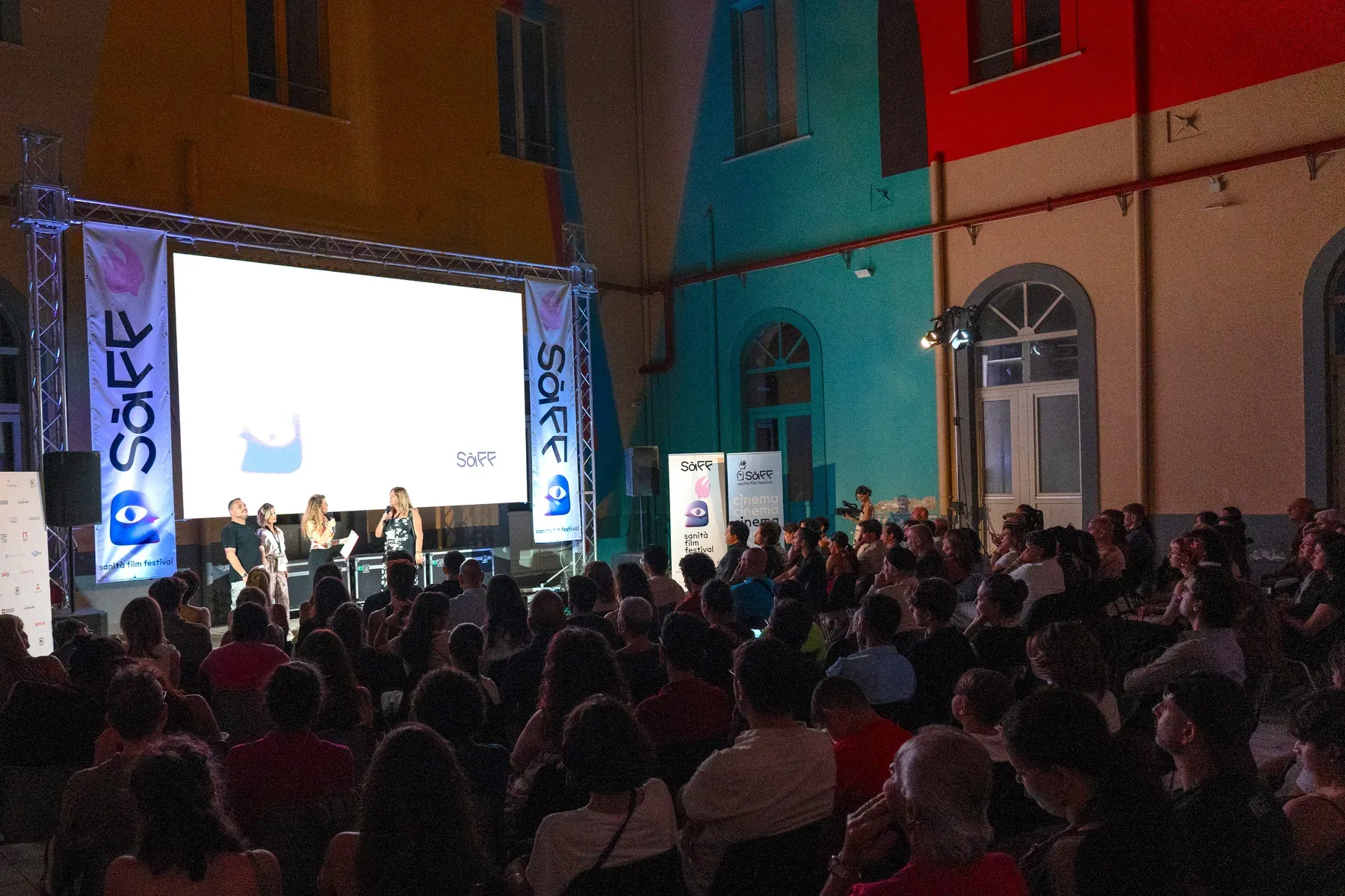 Il pubblico seduto davanti al grande schermo nel cortile, durante una proiezione serale